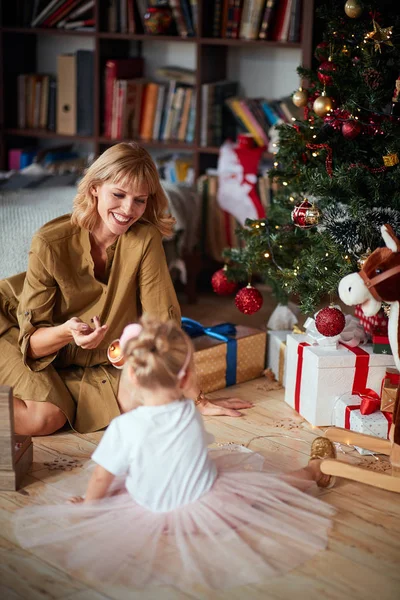 Orgullosa mamá mostrando a su hija cómo decorar un árbol de Navidad — Foto de Stock