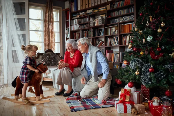 Kerstochtend, peuter meisje op een hobbelpaard — Stockfoto