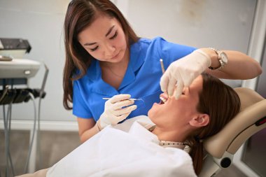 Female dentist in clinic working with patient