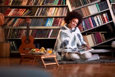 Odadaki büyük kitaba bakan bir kadın.