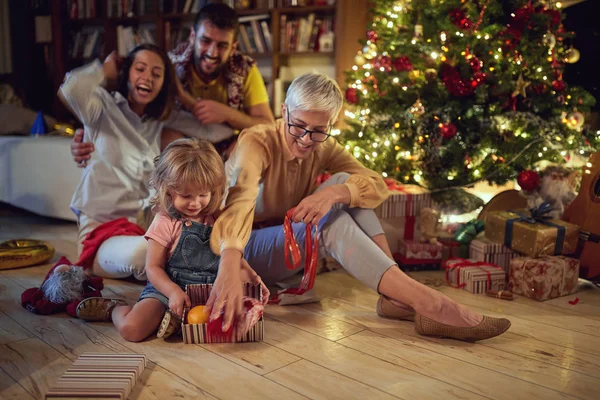 Family open presents in a room with a Christmas tree on Christma — Stok fotoğraf