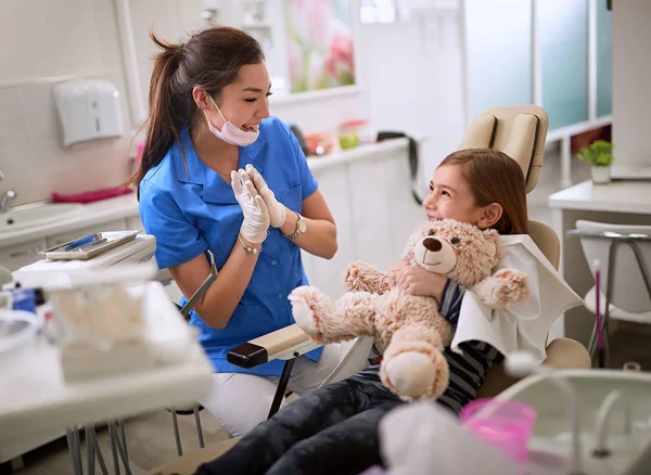 Dentista rilassa ragazza in sedia dentale — Foto Stock