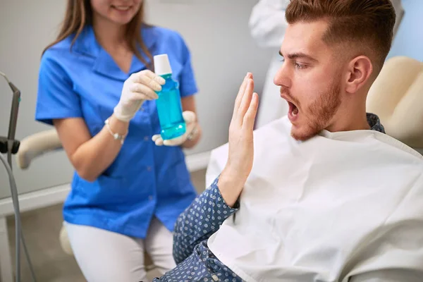 Dental assistant showing mouthwash to patient — Stockfoto