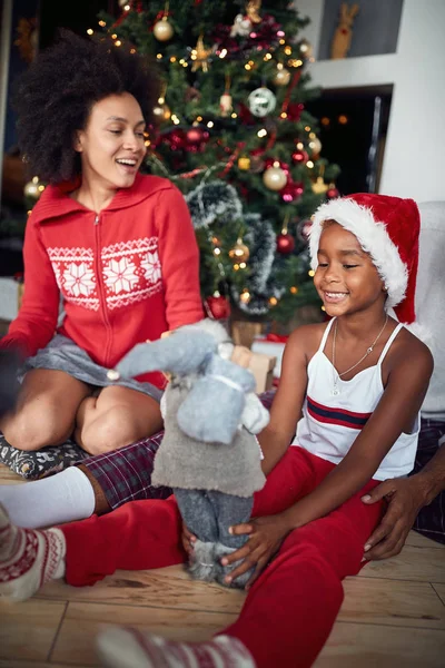 Lächelndes Mädchen spielt mit Weihnachtsgeschenk und feiert Weihnachten wi — Stockfoto