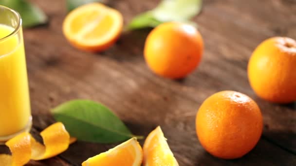 木の背景にオレンジとジュースをガラスで切り — ストック動画