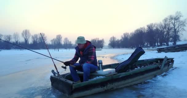 Pescatore Pesca Dal Buco Nel Lago Ghiaccio Dalla Sua Barca — Video Stock