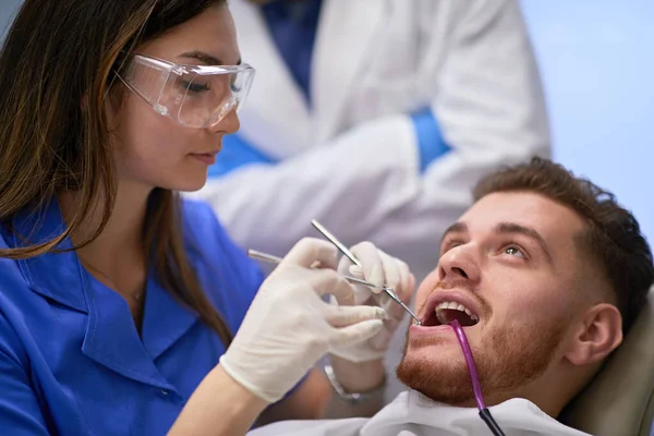 Dentista feminina trabalhando em seus pacientes dentes — Fotografia de Stock