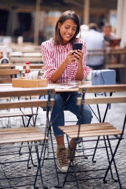  Kadın kafede kahve içiyor ve telefon kullanıyor..