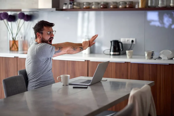 Άνθρωπος χασμουριέται το πρωί, ενώ τον έλεγχο e-mail σε ένα φορητό υπολογιστή — Φωτογραφία Αρχείου