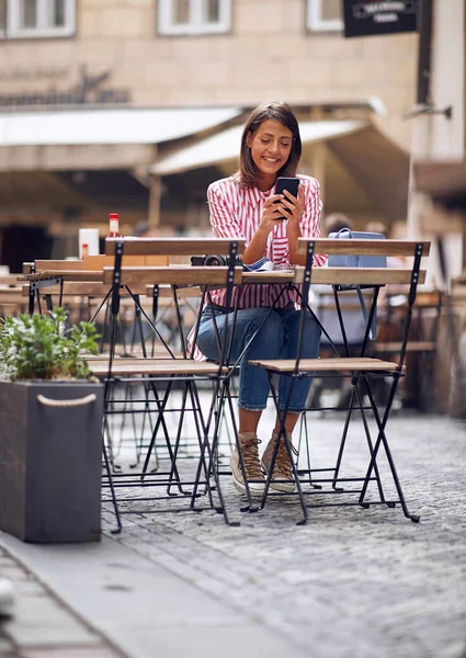 Mädchen benutzt Telefon und trinkt Kaffee im Café. — Stockfoto