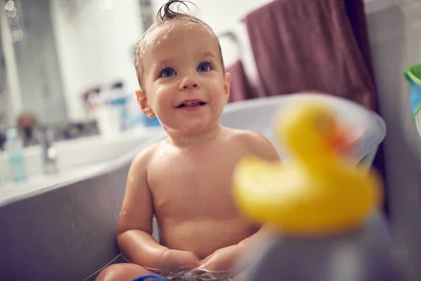 Bebê engraçado tomando um banho brincando com brinquedos. Criança pequena em um b — Fotografia de Stock