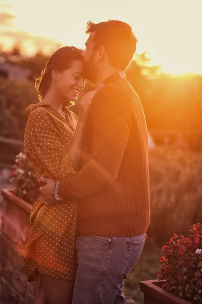 Casal alegre abraçando e beijando ao pôr do sol — Fotografia de Stock