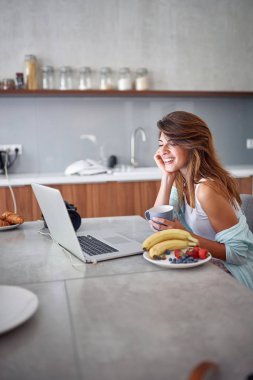 Kız laptopla çalışırken kahvaltı yapıyor..