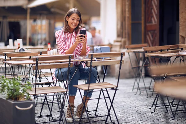 Flicka som använder telefon och dricker kaffe i caféet. — Stockfoto