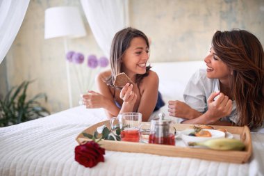 Seksi homoseksüel çift yatağında sağlıklı bir kahvaltı yapıyor.