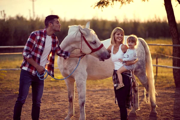 Mam en pap laten het paard aan een klein meisje zien. Plezier op het platteland — Stockfoto