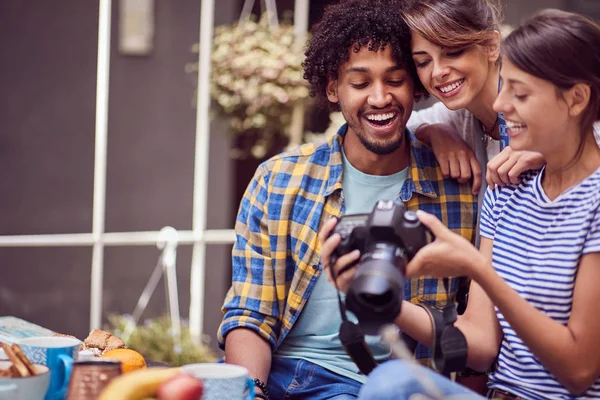 Grupo de jovens amigos olhando para câmera e falando sobre foto — Fotografia de Stock