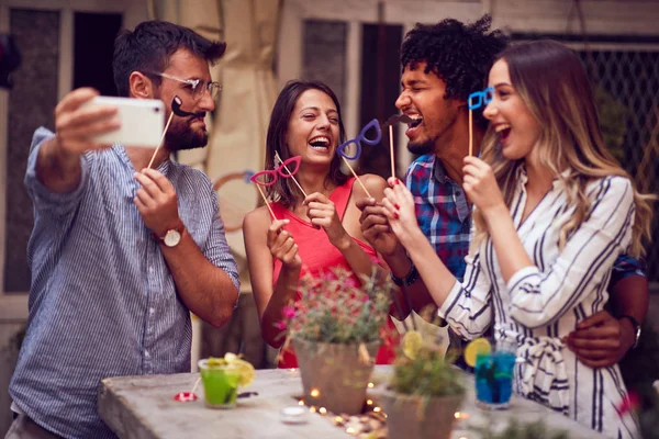 Grupo feliz de amigos se divertindo com adereços no pau na noite — Fotografia de Stock