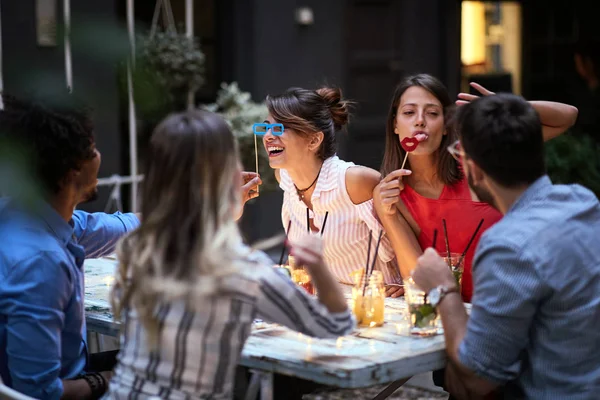 Grupo feliz de amigos se divertindo com adereços no pau na noite — Fotografia de Stock