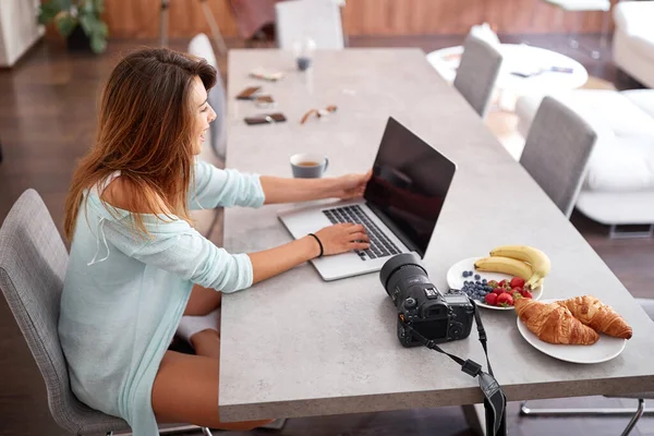 Ung kvinna skrattar och skriva på bärbar dator medan du sitter på en stol — Stockfoto