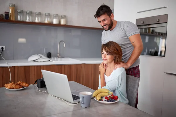 Junges erwachsenes Paar, das in der Küche auf dem Laptop Inhalte anschaut. lässig — Stockfoto