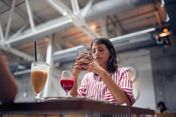 Kvinna sitter på café och sms vänner — Stockfoto