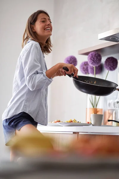 Mulher sorrindo preparando ovos para o café da manhã na manhã brilhante — Fotografia de Stock