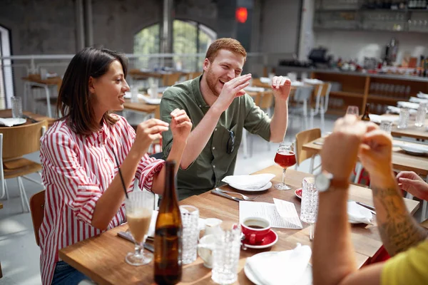 Young adults talking and smiling in restaurant. Conversation, fr — ストック写真