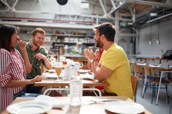 Group of young adults talking and smiling in restaurant — Zdjęcie stockowe