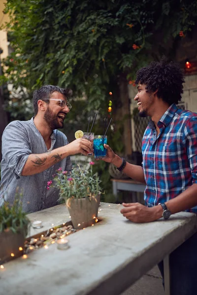 Dois jovens macho multiétnico rindo e brinde com coquetéis em — Fotografia de Stock