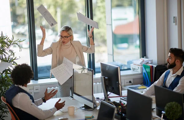 angry female boss throwing papers away in front of two employees