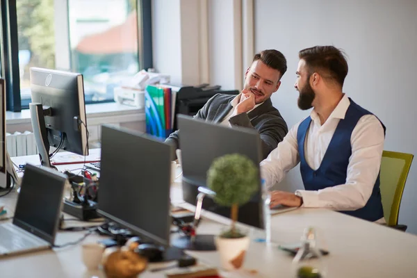 Two male colleagues gossip at work in open space office — Stok fotoğraf