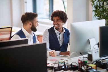 İki genç iş arkadaşı, çok ırklı, ofiste konuşuyor ve gülümsüyor. iş, modern, ofis, çok ırklı, kavram