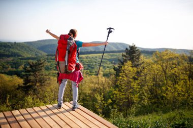 Kadın yürüyüşçü panorama seyrediyor ve doğada özgürlüğü hissediyor.