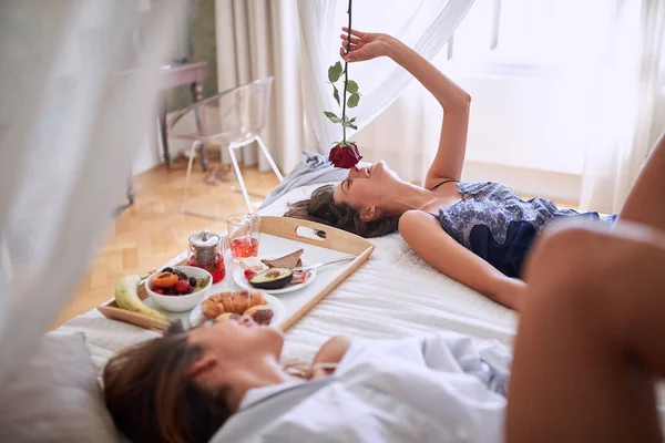 lesbians laying, breakfast in bed, smelling the rose. lesbian, couple, romantic, breakfast in bed concept