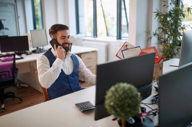 Gülümseyen işadamı cep telefonu kullanıyor. Modern ofiste genç bir iş adamı..