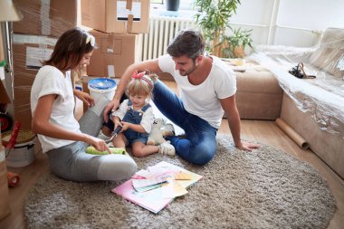 Üç kişilik genç bir aile yeni dairede bir katta oynuyorlar. Yeni daire, yeni başlangıç, neşe, mutluluk konsepti