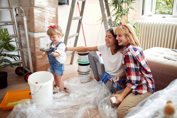 two female friends laughing with cute little girl while renovating apartment. renovation, apartment, communication, joy,  happiness  concept