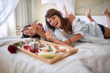 lezbiyen, çift, yatakta kahvaltı, romantizm konsepti. Lezbiyenler gülüyor, yatakta kahvaltı yapıyorlar..