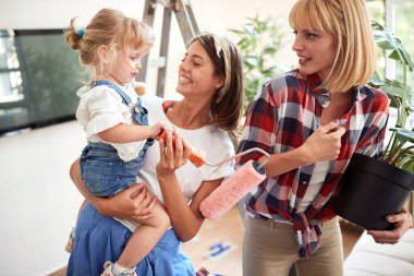 İki kız arkadaş apartman dairesini yenilerken küçük tatlı bir kızla eğleniyorlar. Yenileme, daire, iletişim, aşk, konuşma konsepti