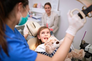 Dişçi koltuğunda ağzı açık genç bir kadın hasta.