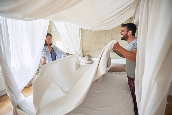若いカップルが喜びを持って寝室にシーツを広げていました ベッドルーム ルーチン 幸福の概念 — ストック写真