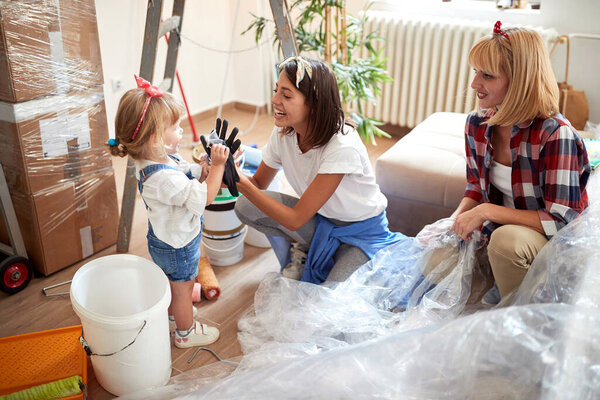 two female friends playing with cute little girl while renovating apartment. renovation, apartment,  communication, joy,  happiness  concept