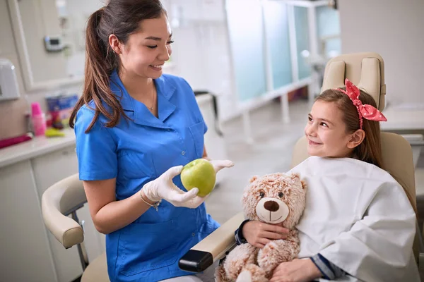 Genç Dişçi Dişçi Koltuğunda Çocuğa Elma Gösteriyor — Stok fotoğraf