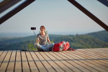 Dağda bacak bacak bacak üstüne atmış bir kadın selfie çekiyor. Doğa, rahatlama, rahatlama, pozitif, enerji kavramı