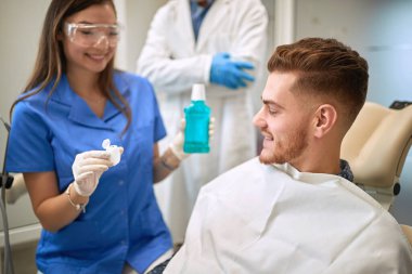 Kadın dişçi hasta ürünlerine oral bakım için gösteriyor 
