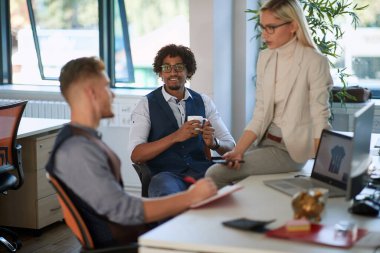 Ofisteki meslektaşlar kahve molasında tartışıyor ve gülümsüyor..