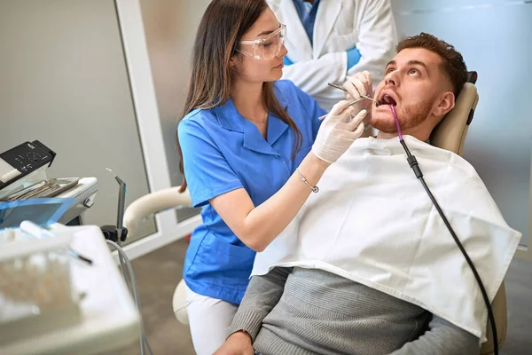 Female dentist repairing tooth to scared man