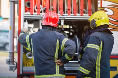 İtfaiye arabasının önündeki üniformalı itfaiyeci kurtarıp koruyacak. Acil durum, tehlike, hizmet kavramı. 