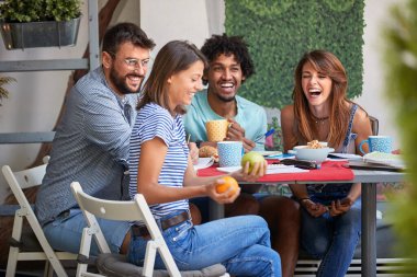 Bir grup neşeli arkadaş öğrenirken dışarıda eğleniyorlar.